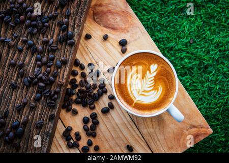 Cappuccino und Kaffee Bohne auf Holz Textur Hintergrund. Frühstück am Morgen oder Kaffee. Stockfoto
