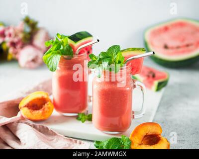 Frisch gekochte Wassermelone und Peach Smoothies in Maurergrug und Metallstroh Stockfoto