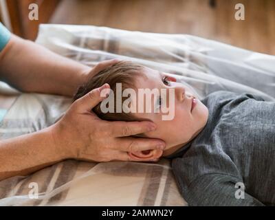 Osteopathie-Behandlung. Elementares Alter die Stirn des Jungen wird von einem echten osteopathischen Arzt manipuliert Stockfoto