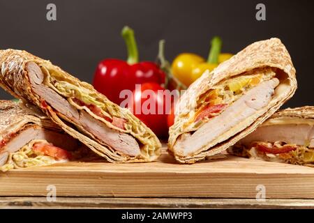 Shawarma chicken Roll in ein Fladenbrot mit frischem Gemüse und Sauce auf Holz- Hintergrund. Selektiver Fokus Stockfoto