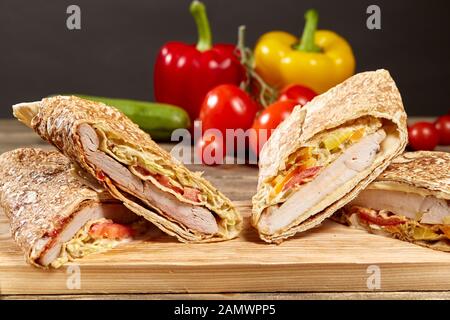Shawarma chicken Roll in ein Fladenbrot mit frischem Gemüse und Sauce auf Holz- Hintergrund. Selektiver Fokus Stockfoto