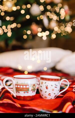 Romantic atmosphere and hot cocoa cups. Holiday lights and red plaid Stockfoto