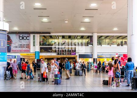 Horley, Großbritannien - 28. Juni 2018: Flughafen Gatwick London Terminal mit Menschen, die in Gebäudearchitektur und Abfahrtsschild zu Fuß unterwegs sind Stockfoto