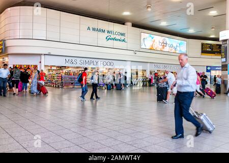 Horley, Großbritannien - 28. Juni 2018: Flughafen Gatwick London Terminal mit Leuten, die in Gebäudearchitektur gehen und für M&S Lebensmittelgeschäft einfach foo unterschreiben Stockfoto