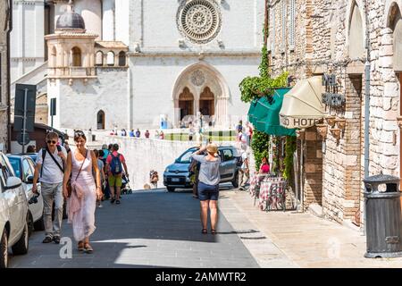 Assisi, Italien - 29. August 2018: Blick auf die Papstbasilika des Heiligen Franziskus von Assisi mit Menschen, die auf einer schmalen Gasse spazieren gehen Stockfoto
