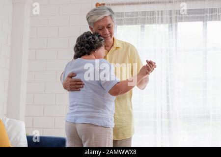 Asiatischer seniors Paar genießen Tanzen im Wohnzimmer zu Hause. Altern zu Hause Konzept Stockfoto