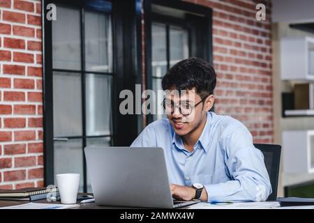 Asiatische Geschäftsmann Woking mit Laptop und Papier Arbeiten am Schreibtisch im Büro. Digital Workflow online Business Lifestyle Konzept Stockfoto