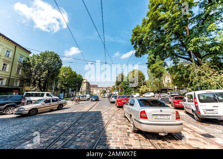 Lwiw, Ukraine - 1. August 2018: Trolleystraßenbahngleise in der historischen ukrainischen Stadt in der Altstadt mit vielen Autos auf Straße und Stromleitungen Kabel Menschen Stockfoto