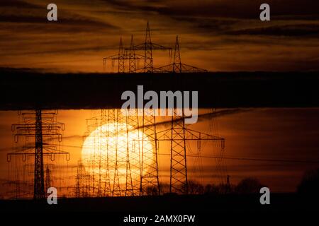 15. Januar 2020, Baden-Württemberg, Schwieberdingen: Die Sonne steigt hinter Hochspannungspylonen auf. Foto: Sebastian Gollnow / dpa Stockfoto