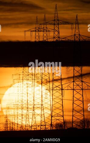 15. Januar 2020, Baden-Württemberg, Schwieberdingen: Die Sonne steigt hinter Hochspannungspylonen auf. Foto: Sebastian Gollnow / dpa Stockfoto