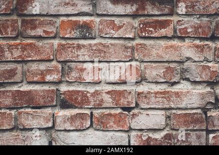 Alte rote Ziegelsteinmauer im rustikalen Stil. Zementwand, Grunge Textur. Hintergrundbild mit brauner Kulisse. Grober Jahrgang gerissene Ziegelei. Strukturierte Hintergründe. Konz Stockfoto