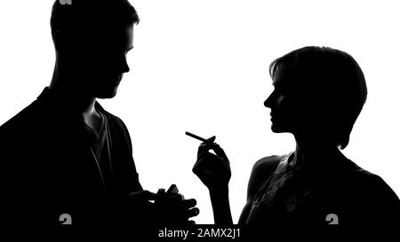 Junge Dame, die zu Mann geht und Zigarette anzündet, flirtet bei Party-Bekanntschaft Stockfoto