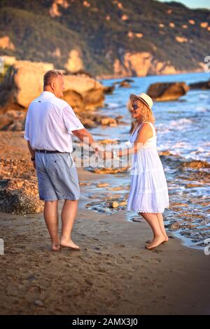Ein lächelndes Paar für Erwachsene, das gerne am Strand spazieren geht Stockfoto
