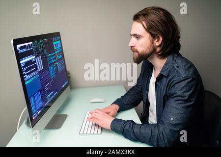 Programmiergerät für Männer, der an einem Desktop-Computer am weißen Schreibtisch im Büro arbeitet. Stockfoto