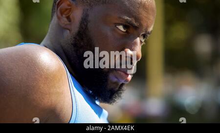 Angesichts der schwitzenden afro-amerikanischen Athletin, die ernsthaft nach vorne blickt, Motivation Stockfoto