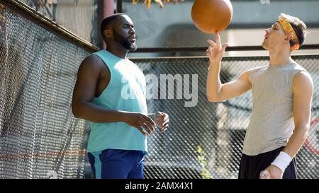Partner von Basketballspielen kommunizieren, Mann dreht Ball auf Finger, Freunde Stockfoto