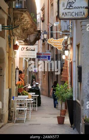 Kleine schmale Straße in der Altstadt von Ortygia, Syrakus, Sizilien, Italien. Restaurant Trattoria O' Scinà Stockfoto