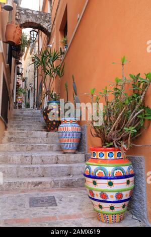 Enge Straße mit bunten Blumentöpfen in Taormina Stockfoto