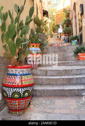 Enge Straße mit bunten Blumentöpfen in Taormina Stockfoto