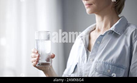 Frau, die Pille in Glas mit Wasser, Frauengesundheit, Medikamenteneinnahme einbringt Stockfoto
