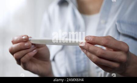 Frau, die einen Schwangerschaftstest in der Hand hält, das Ergebnis betrachtet, Gynäkologie in der Nähe Stockfoto