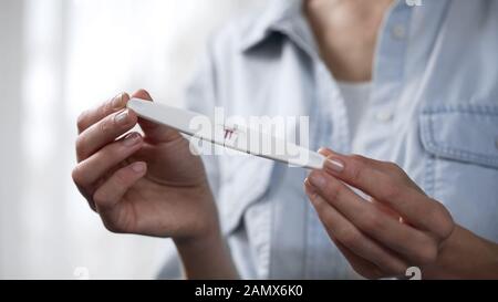 Frauen, die einen positiven Schwangerschaftstest in den Händen halten und ihn vor der Kamera demonstrieren Stockfoto