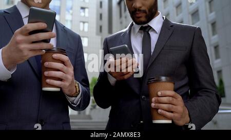 Geschäftsleute lesen E-Mails auf Smartphones zur Kaffeepause, angespannter Arbeitszeitplan Stockfoto