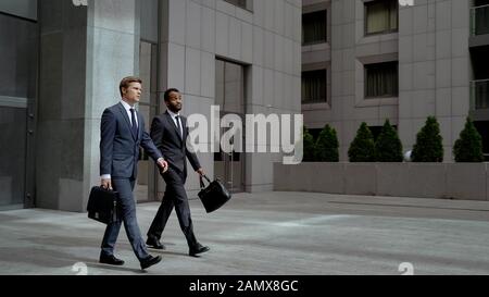 Zwei Mitarbeiter verlassen das Business Center, nachdem sie sich mit Partnern treffen, Business Stockfoto