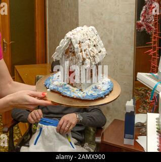 Close-up Lebkuchenhaus auf runden Platine, die in Frau Hände ist in der Wohnlandschaft. Stockfoto