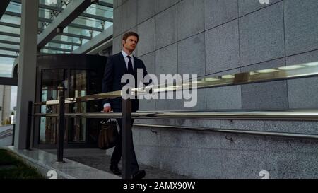 Ambitionierter Geschäftsmann verlässt nach einem erfolgreichen Treffen das Bürozentrum, Routine Stockfoto