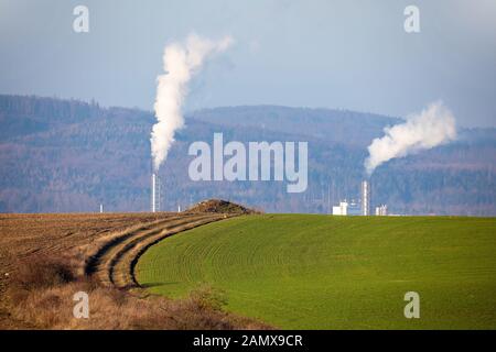 Rauchabgase aus Fabrikrohren, Jihlava Tschechien, Europa. Verborgene Fabrik hinter einem Hügel. Stockfoto