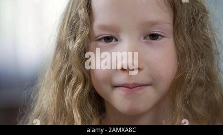 Lustige kleine kaukasische Mädchen, die nach Kamera, Kindheitskonzept, Gesichtsnähe suchen Stockfoto