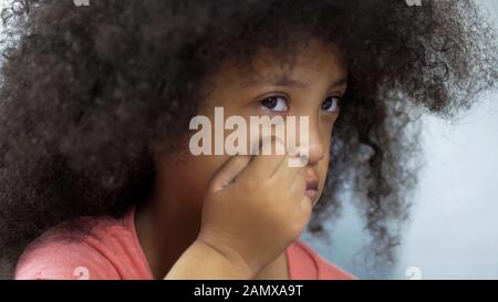 Depressive Mulatto Mädchen, die an einem Tisch sitzen und ein Down-Syndrom haben, Gesundheit Stockfoto