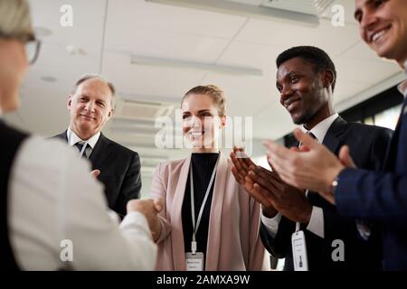 Multiethnische Gruppe von Geschäftsleuten stehen und applaudieren zu dem Führer nach Konferenz Stockfoto