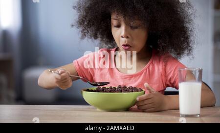 Süßes Mulatto Mädchen, das zum Frühstück Schokoladenkornflocken isst, Risiko für Diabetiker Stockfoto