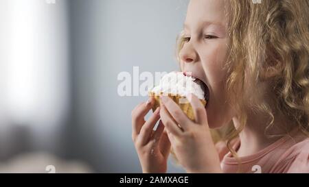 Ziemlich kleines kaukasisches Mädchen, das Kuchen isst und den perfekten Dessertgeschmack genießt Stockfoto