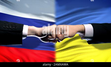 Russland vs. Ukraine-Konflikt, internationale Beziehungen, Fäuste auf Fahnenhintergrund Stockfoto