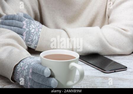 Ein Mann in warme Kleidung sitzt mit einer Tasse heißen Getränk in einem Straßencafe. Close-up. Rest im Winter Sport. Stockfoto