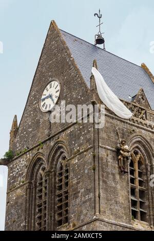 Attrappe des Fallschirmjägers John Steele, der während der alliierten Invasion im zweiten Weltkrieg auf der Spitze der Kirche von Sainte-Mère-Église in der Normandie festsaß Stockfoto