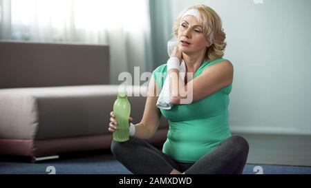 Frau mittleren Alters wischt nach dem Workout mit Handtuch, Wasser-Balance, Gesundheitspflege Stockfoto