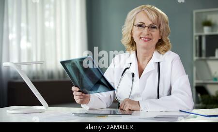 Attraktiver Arzt, der die Lunge des Patienten einscannt, mit einem Lächeln in der Kamera lächelt, Diagnose Stockfoto