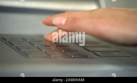 Weibliche Hand mit ATM, einfügen eines persönlichen Codes und Drücken von Tasten Stockfoto