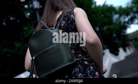 Dame mit elegantem Ledersack, die im Park nach oben geht, bequeme Tasche Stockfoto