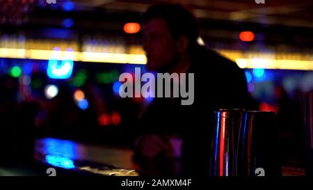 Mann im Anzug, der Getränke an der Bar-Theke bestellt und allein die entspannte Atmosphäre feiert Stockfoto