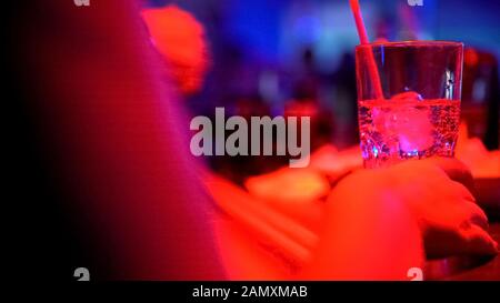 Weibliche Hand mit Glas Alkohol an der Bar-Theke in der Nachtklub-Party, Nahaufnahme Stockfoto