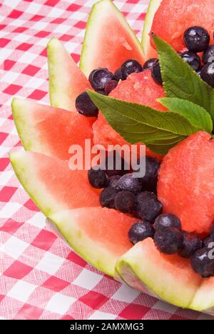 Wassermelon-Obstsalat mit gefrorenen Blaubeeren und frischen Stevia-Blättern für eine Pfändung. Stockfoto