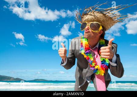 Gerne Unternehmer tragen lustig Sonnenbrille, touristische Strohhut und Lei mit Daumen nach oben Feiern auf einem tropischen Strand Stockfoto
