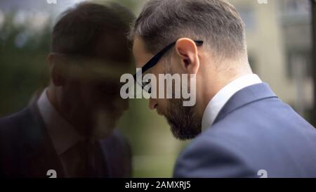 Denkender Manager, der sich an die Bürowand lehnt, Probleme mit Arbeitsausfällen, Frustration Stockfoto