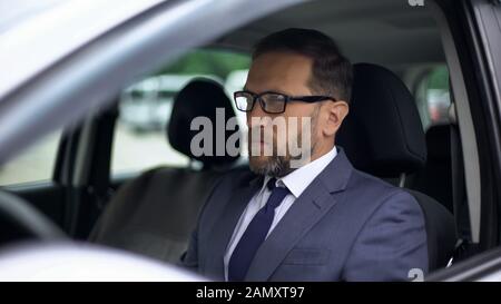Seriöser Geschäftsmann sitzt im Auto, Einsamkeit vor gestresster Arbeit, Tagesplanung Stockfoto