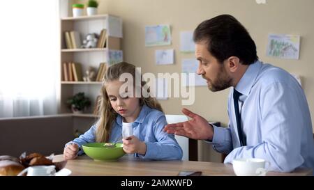 Strenger Vater spricht mit Tochter in Küche, Eltern- und Kinderkonflikt, Familie Stockfoto